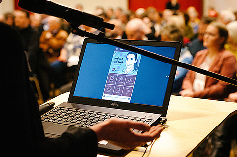 Blick auf Laptop der Referierenden, Publikum unscharf im Hintergrund